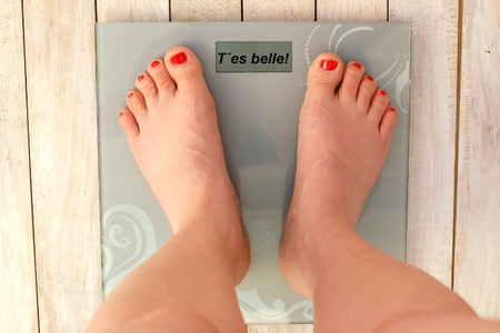 Feet on scales with text You are beautiful in French language on the wooden background.Beaty and...