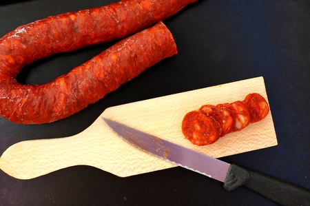 Chorizo on the wood with knife on the black background, overhead horizontal viewの写真素材