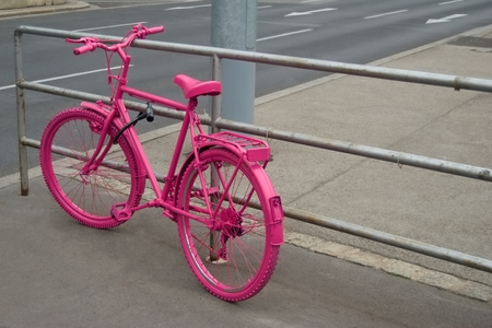 Pink painted bicycle locked to the railingの写真素材