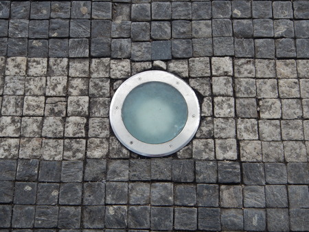 a roung light in a cobble stone pavementの写真素材