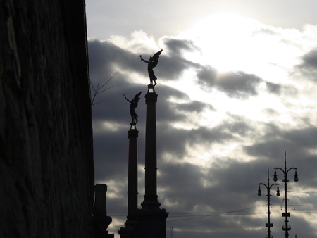 two silhouettes of statues with wings on pillarsの写真素材