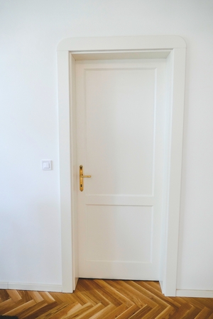 detail of a white door with a wooden floor at homeの写真素材