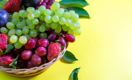 Assorted fresh fruits in a basket on a yellow background, close upの写真素材