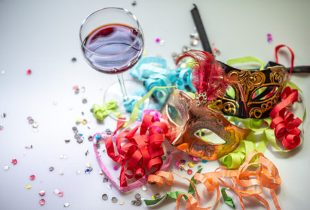 Carnival mask with red wine and confetti on white background