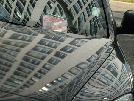 Reflection of an office building and advertising bilboard in mirror surface of a carの写真素材