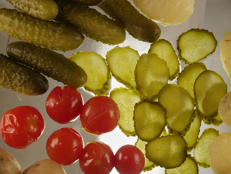 The traditional snack in the village. Boiled potatoes with pickled cucumbers and tomatoes. Flat lay. Back lit on glass backgroundの写真素材