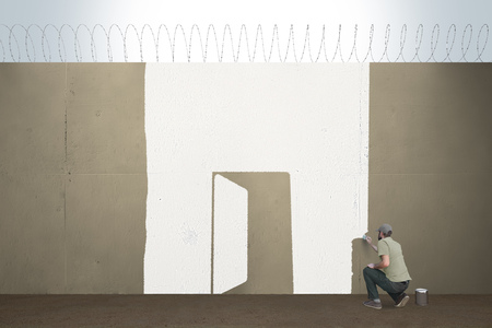 A man draws a open door on a border barrier.の写真素材