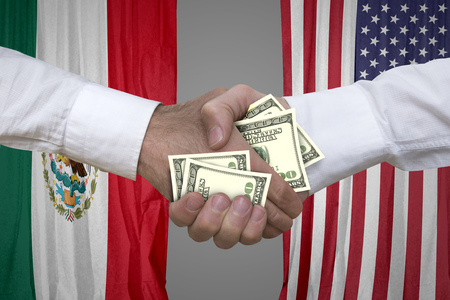 100 dollar bills handshake with USA and Mexican flags background.の写真素材