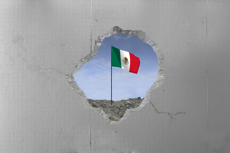 Mexican flag behind a concrete wall.の写真素材