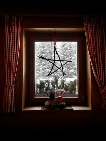Snow blizzard watched from inside a rural cabin with Christmas decoration, italian Alps, Alto Adige/Sudtirol region.の写真素材