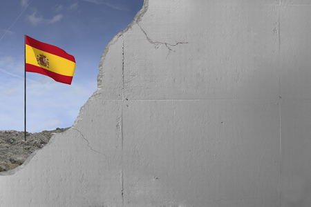Spanish flag behind a concrete wall.の写真素材