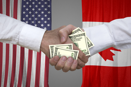 100 dollar bills handshake with USA and Canadian flags background.の写真素材