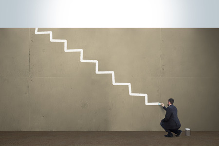 A business man draws stairs on a concrete barrier.の写真素材