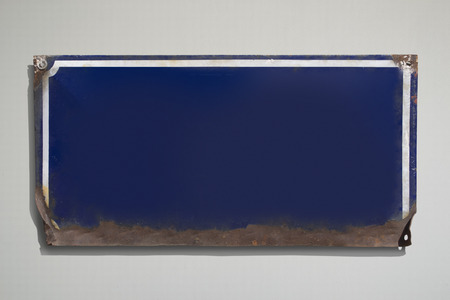Rusty blue metallic sign with grey background.の写真素材