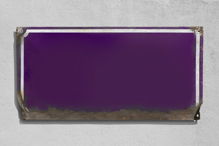 Rusty violet metallic sign with rough wall background.の写真素材