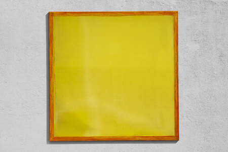 Yellow screen printing frame used as sign with rough wall background.の写真素材