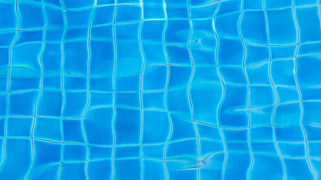 Rippled water in swimming pool with sun reflection