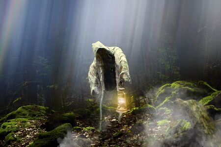 Ghost or phantom with lantern in mysterious and magic forest .Beautiful mysterious magic forest full of light, sun and fog. Apparition in forest.の写真素材