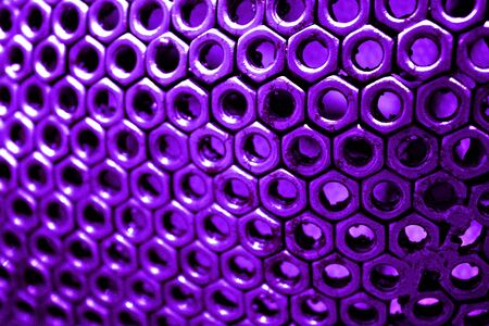 Nuts fasteners one next to other forms and pattern.Steel art in pink to purple tones.Very many nuts fasteners in a row form an unusual background and texture.の写真素材