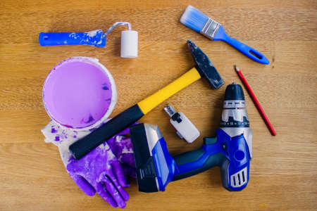 Reconstruction can begin. Concept with hand tools.Cordless drill, tape measure, pencil, roller, lilac paint, brush, hammer and dirty work gloves.の写真素材