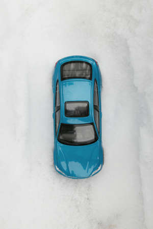 Bird`s eye view of blue passenger car in deep snow.A blue passenger car without a driver stands on the road in deep snow. The road is not visible through the snow.の写真素材