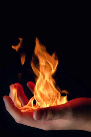 Detail of hot flames on the palm isolated on black background.の写真素材