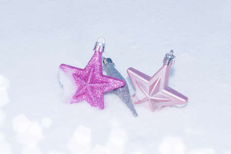 Three Christmas decorations lie in the snow. Christmas is leaving. Or are they coming? Two stars,...