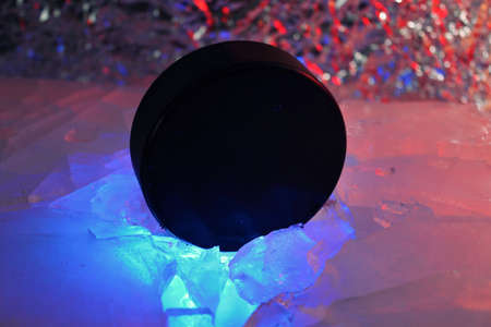 Hockey puck stands on the edge in cracked ice. A red-blue light falls on him. Czech hockey concept. The hockey puck broke the ice. Long live the World Hockey Championship.の写真素材
