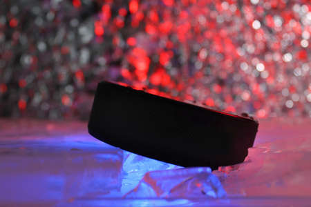 Hockey puck stands on the edge in cracked ice. A red-blue light falls on him. Czech hockey concept. The hockey puck broke the ice. Long live the World Hockey Championship.の写真素材