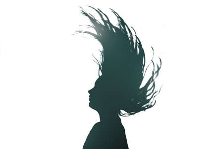 Black silhouette of a girl or woman who raises her head and throws her hair on her back.の写真素材