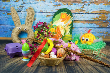 Color eggs decorated with wax and glitter and Easter decoration in a basket and branches of ornamental cherries.の写真素材