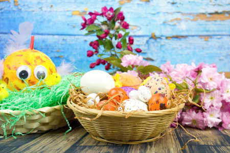 Color eggs decorated with wax and glitter and Easter decoration in a basket and branches of...