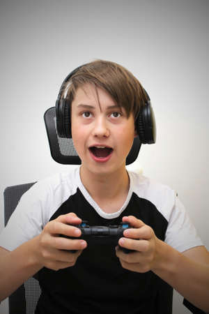 The boy is playing a computer game and sitting on a gaming chair. He is excited about winning.