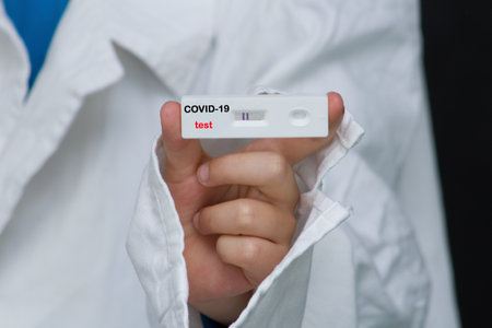 The doctor is holding a positive antigen test for covid. With this test, you can test yourself at home using saliva or a nasal swab.の写真素材