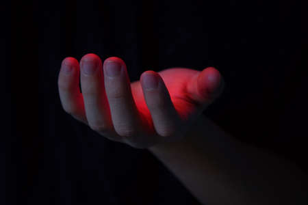 The palm from which it emits red light. Magical abilities and activation of energy in the body.Red light on the palm. Heat entering the body. Magical abilities, enchantment and spirituality.の写真素材