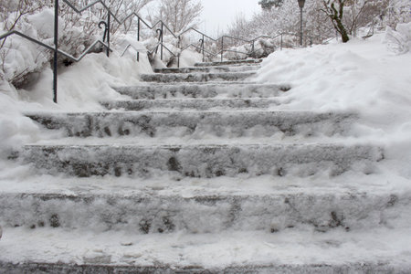 Long stairs covered with a layer of snow. Watch out for ice. Beware of slipping. It's bitterly cold. You won't freeze to the railing.の写真素材
