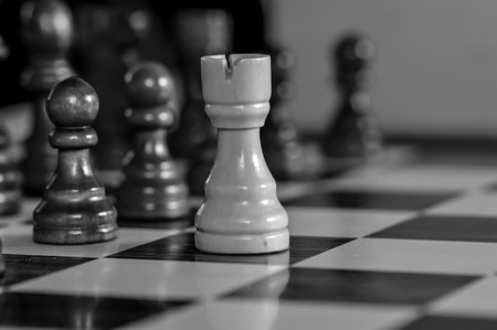 Chessboard with white pawn in front of brown pawns in black and whiteの写真素材