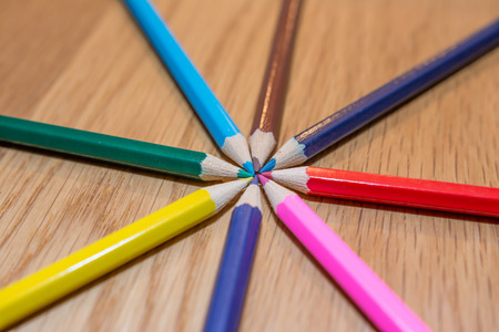 Color pencils in circle on wooden table