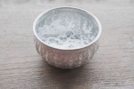 Ice water in the Thai silver bowl is placed on the plank, Beautiful Thai tradition hospitality.