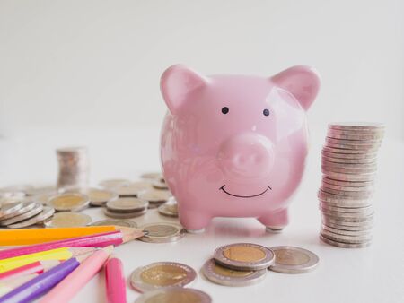 Pink Piggy bank, and bright colored pencils  with coins pile, Saving money for future plan and retirement fund concept.の写真素材