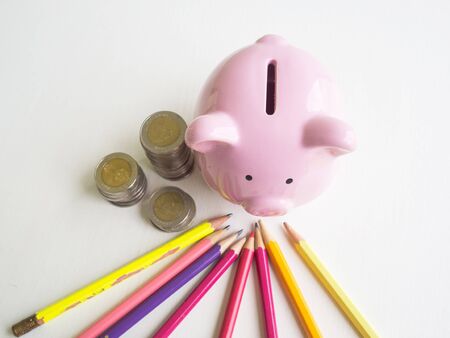 Pink piggy bank with coins pile and Bright colored pencils, Saving money for future plan and retirement fund concept.の写真素材