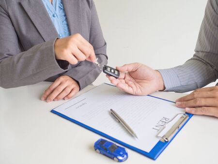 Car saleswoman giving the key to customer and signed a car rent service lease contract.の写真素材