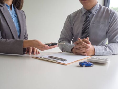 Car saleswoman giving the key to customer after signed a car rental service lease contract.の写真素材