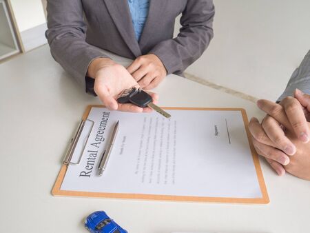Car saleswoman giving the key to customer and signed a car rental service lease contract.の写真素材