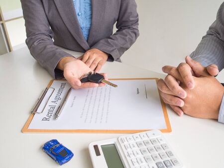 Car saleswoman giving the key to customer and signed a car rental service lease contract.の写真素材