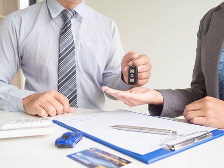 Salesman give key to customer Business woman after signed  a car rent service lease contract.の写真素材