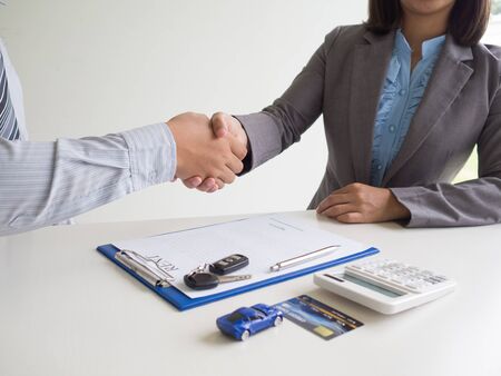 Customer woman used credit card and signed for rent car form salesman, Shake hands deal business.の写真素材