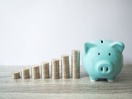 Blue piggy bank with coins pile growth graph, saving money for future investment plan and retirement fund concept.の写真素材