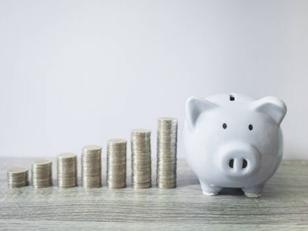 White piggy bank with coins pile growth graph, saving money for future investment plan and retirement fund concept.の写真素材
