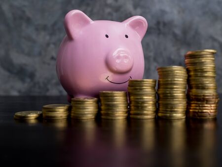pink piggy bank with growth coins bar graph on black cement wall background, Saving money for future...